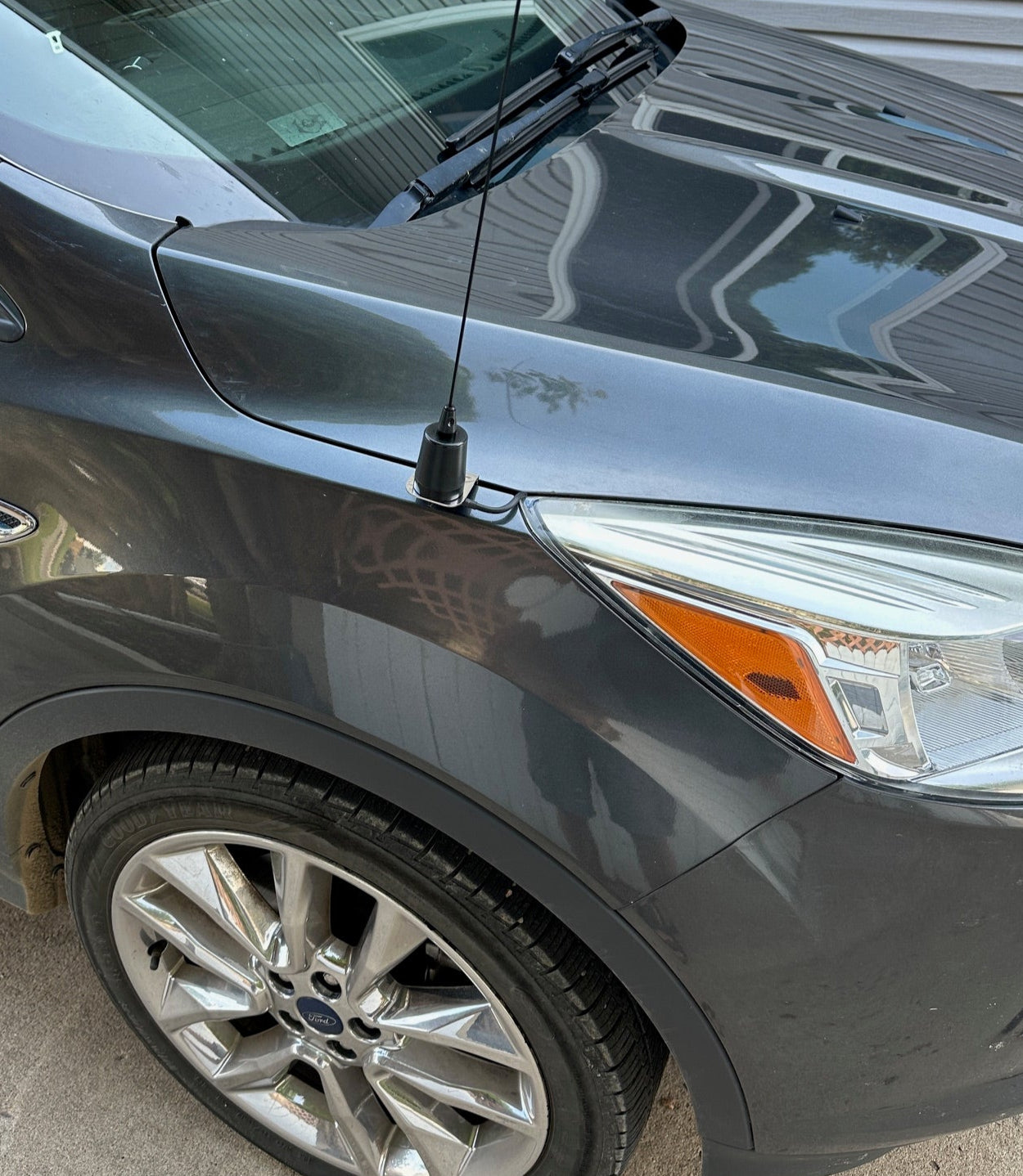 Close-up of a car's side mirror and wheel on a gray pavement. Alberta Radio Supply